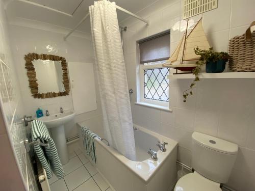 a bathroom with a toilet and a sink and a tub at Leeward Lodge in Totland