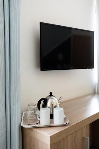 a shelf with two cups and a tea pot and a television at Fleming Suites by Hili in Rome