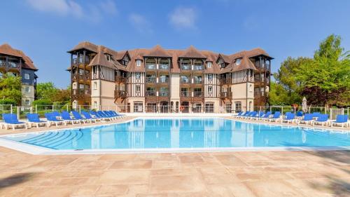une grande piscine avec des chaises et un bâtiment dans l'établissement Appart 2 chambres Piscine chez ROX - Résidence du Golf, à Deauville