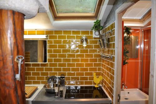 ユゼスにあるLa Maisonnette romantiqueの黄色のレンガの壁、シンク付きのキッチン