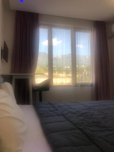 1 dormitorio con cama y ventana grande en Smart Lugano Apartment, en Tirana