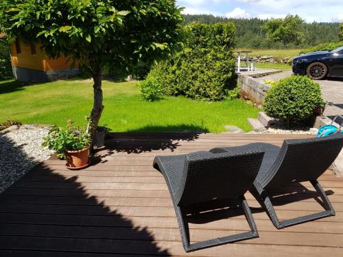 two chairs sitting on a deck next to a tree at Auszeit am Wildkatzenpfad in Bad Herrenalb