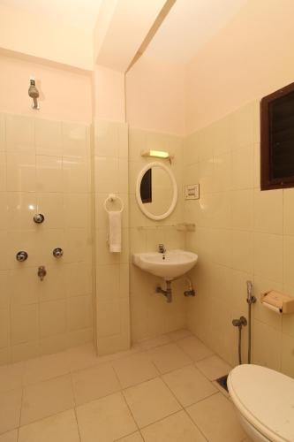 W łazience znajduje się umywalka, toaleta i lustro. w obiekcie Agarwal's Residency w mieście Visakhapatnam
