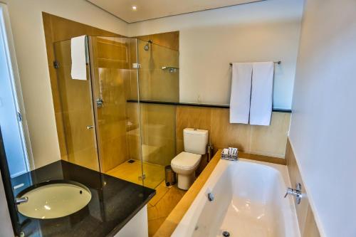 a bathroom with a tub and a toilet and a sink at Canelands Beach Club in Ballito