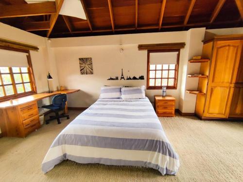 a bedroom with a large bed and a desk at Casa Guaymaral. Encantadora, rural y espaciosa in Bogotá