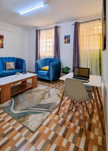 - un salon avec un canapé bleu et une table avec un ordinateur portable dans l'établissement Spacious 1br Fully Furnished with Parking Nakuru, à Nakuru
