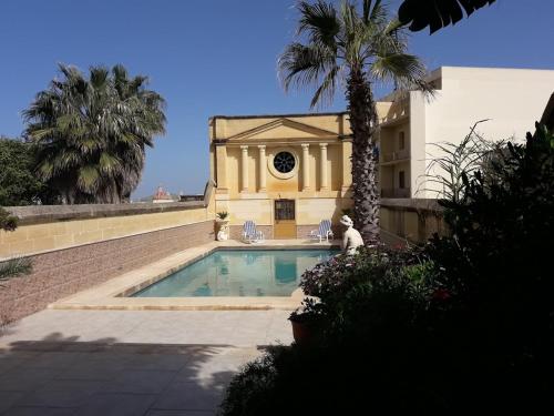 una casa con piscina e una palma di Palma Residence with Communal Pool a Sannat