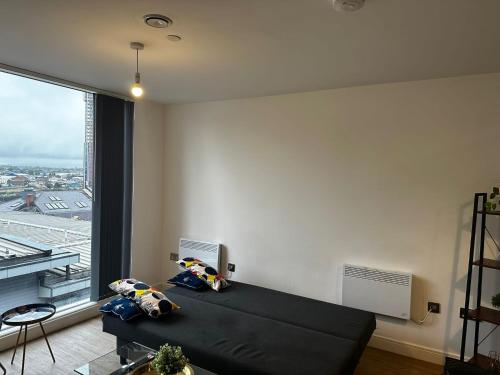 a bedroom with a black bed and a large window at At home Property in Manchester