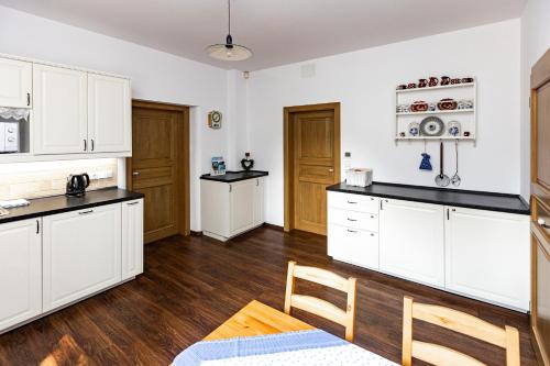 a kitchen with white cabinets and a wooden floor at Penzion Na Fojtství in Zašová