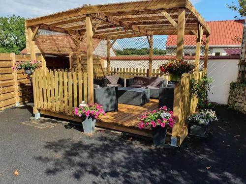 a wooden gazebo with a couch and flowers at La Cantraigne gite de 6 à 8 pers. in Audembert