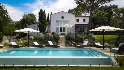 une piscine avec chaises et parasols devant une maison dans l'établissement Villa White, à Saint-Tropez