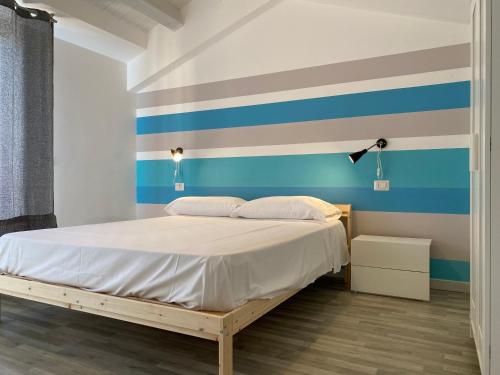 a bedroom with a bed with a striped wall at Marina di Petrolo Apartments in Castellammare del Golfo