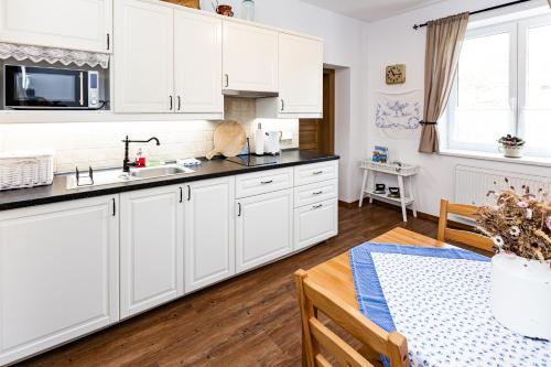 a kitchen with white cabinets and a table at Penzion Na Fojtství in Zašová