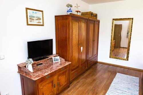 a living room with a television and a wooden cabinet at Penzion Na Fojtství in Zašová