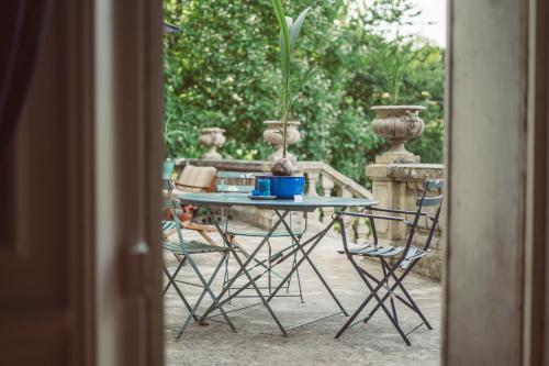 una mesa con sillas y una maceta en un patio en Chambre d’hôtes au Château Le Bas Bleu, Anaïs Nin, en Quesnoy-le-Montant