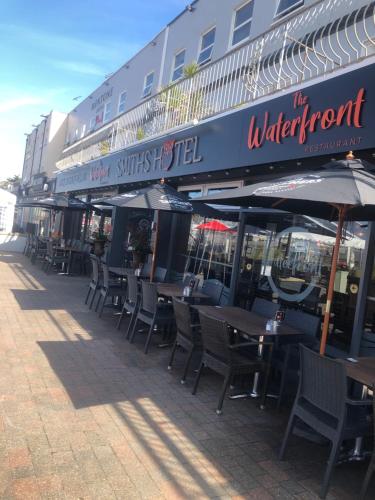 a row of tables and chairs with umbrellas on a street at Smiths Hotel in Weston-super-Mare