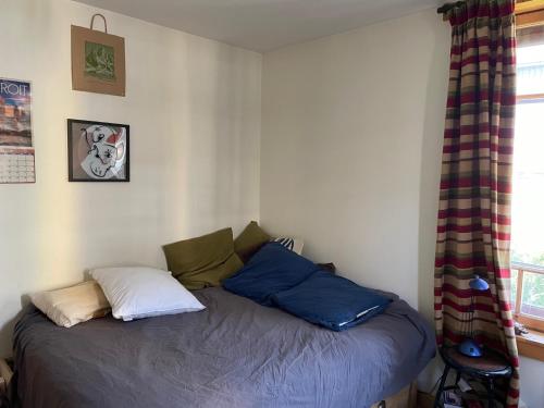 a bedroom with a bed with blue pillows and a window at A Room in Grands Charmoz in Chamonix-Mont-Blanc