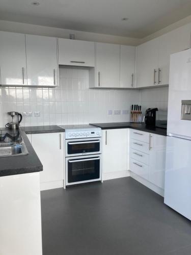 uma cozinha branca com um fogão e armários brancos em CASA DE' COLE' em Barking