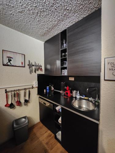 uma cozinha com um lavatório e um balcão em La Petite Corneille - a chic and central studio. em Le Monêtier-les-Bains