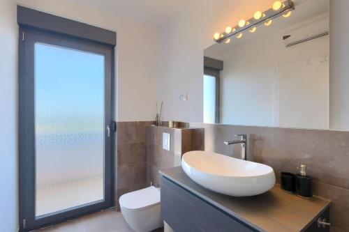 a bathroom with a sink and a toilet and a mirror at Luxury villa Hedone with pool in Rakalj in Rakalj