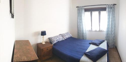 a bedroom with a blue bed and a window at Santa Cruz in Silveira