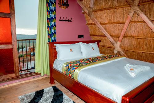 a bed in a room with a balcony at Masaka Cultural Resort in Masaka