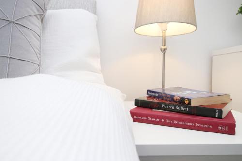 a stack of books sitting on a bed with a lamp at Modern Guesthouse, Fast Wi-Fi, Street Free Parking, Central, Fully Equipped in Cardiff