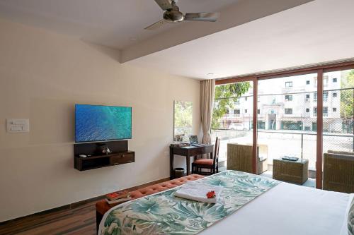 a bedroom with a bed and a flat screen tv at Sapphire Sands by StayVista with Pvt Pool, 4 Jacuzzi at Siolim, Goa in Siolim