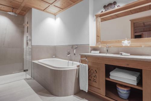 a bathroom with a tub and a sink and a mirror at Hotel La Perla: The Leading Hotels of the World in Corvara in Badia