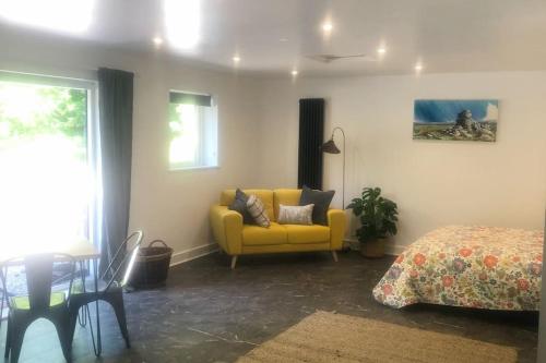 a living room with a yellow couch and a bed at Sharp Tor Riverside Studio Apartment in Plymouth