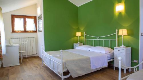 a green bedroom with a bed and two lamps at Villa Domus - Homelike Villas in Montegiorgio