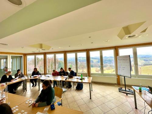 a group of people sitting at tables in a room with windows at eckbergerhof in Gamlitz