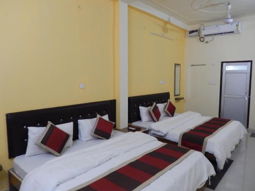 2 camas en una habitación de hotel con almohadas blancas y rojas en Ranthambhore Tiger Hut, en Sawāi Mādhopur