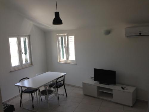 a white living room with a table and a tv at Villa Neka in Primošten