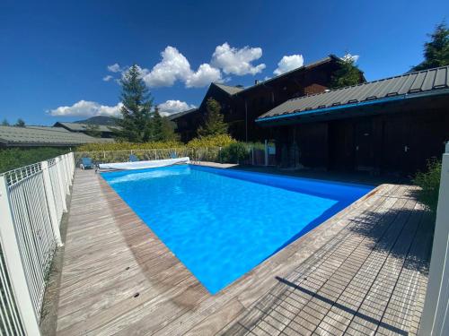 une piscine avec une terrasse en bois à côté d'une maison dans l'établissement Duplex avec piscines et parking proche centre Samoëns - FR-1-624-12, à Samoëns