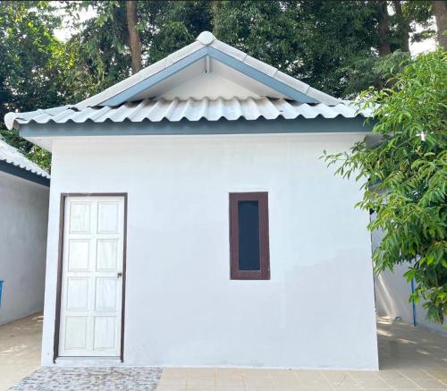 Ban Nong Pla Lai的住宿－Kunaeng ครัวกันเอง รีสอร์ท，一座白色的小建筑,设有窗户和门