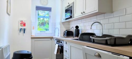 a white kitchen with a sink and a window at Tregenna Castle Resort in St Ives