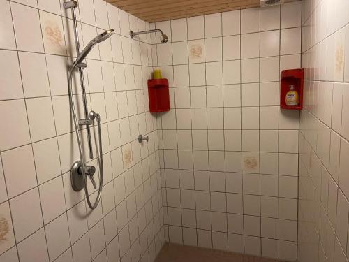 a white tiled bathroom with a shower with a red extinguisher at Ferienhaus Mangels in Steinau
