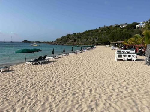 a beach with chairs and umbrellas and the ocean at Friar's beach - Luxurious unit by the beach in Friar's Bay