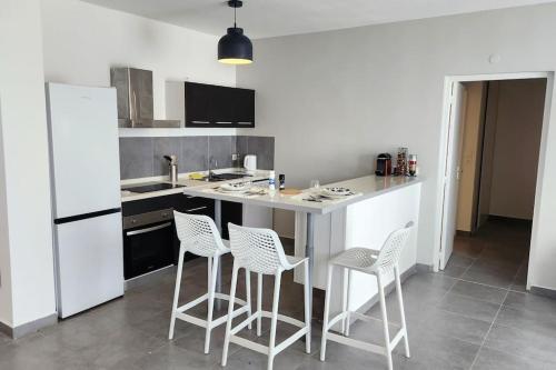 a kitchen with white appliances and white stools at Friar's beach - Luxurious unit by the beach in Friar's Bay