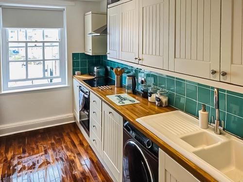 a kitchen with white cabinets and green tile at The Merchants House in Plymouth