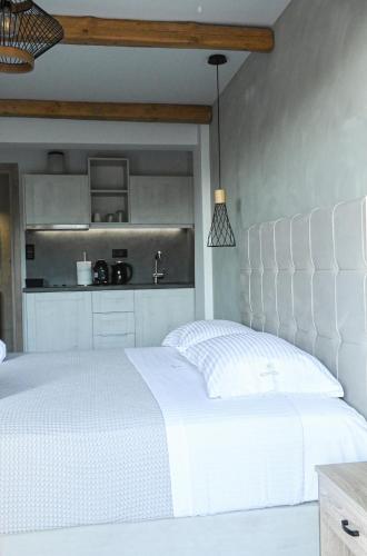 a bedroom with a white bed and a kitchen at Komody in Delfoi
