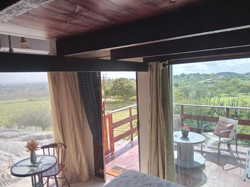 a room with a balcony with tables and a sliding glass door at Chalé Adventure - Serra de São Bento RN in Serra de São Bento