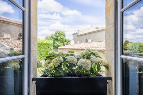 an open window with a pot of flowers on a window sill at Hotel Porte Brunet in Saint-Émilion