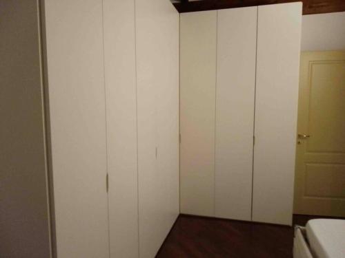 ein weißes Zimmer mit weißen Schränken und einer Tür in der Unterkunft da Luigi - casa Sofia in Cremona