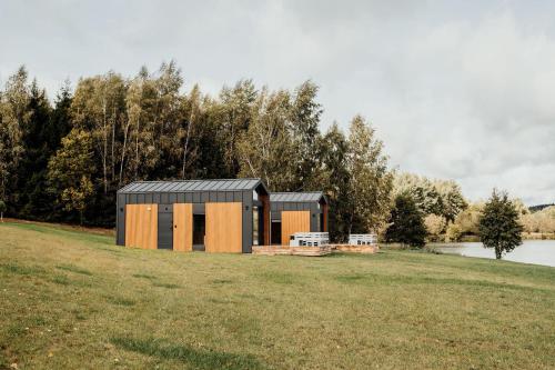 a small house in a field next to a lake at Osada Jaćwingów in Gołdap