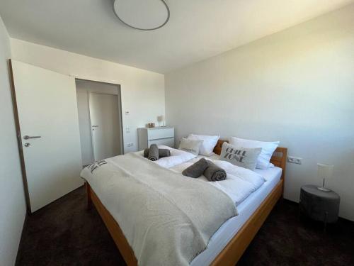 1 dormitorio con 1 cama grande con sábanas y almohadas blancas en Sonnige Wohnung mit schöner Aussicht in Wolfurt, en Wolfurt