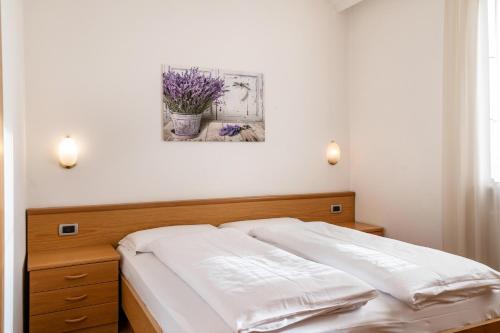 a bed in a bedroom with a painting on the wall at Villa Lory 1 in Canazei