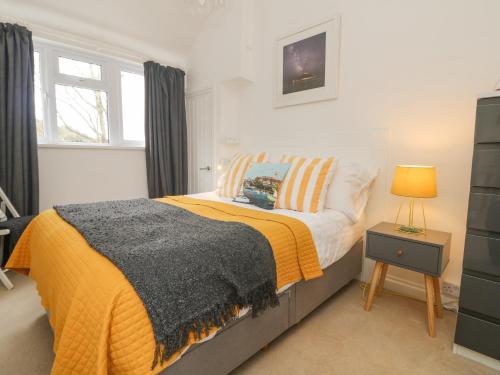 a bedroom with a bed with a yellow blanket at Mackerel Sky in Marazion