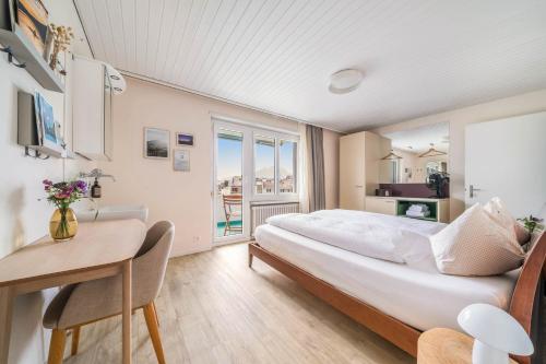 1 dormitorio con 1 cama grande, escritorio y balcón en Wanderlust Guesthouse en Weggis